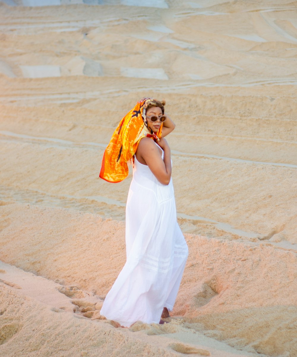 a woman in a white dress talking on a cell phone