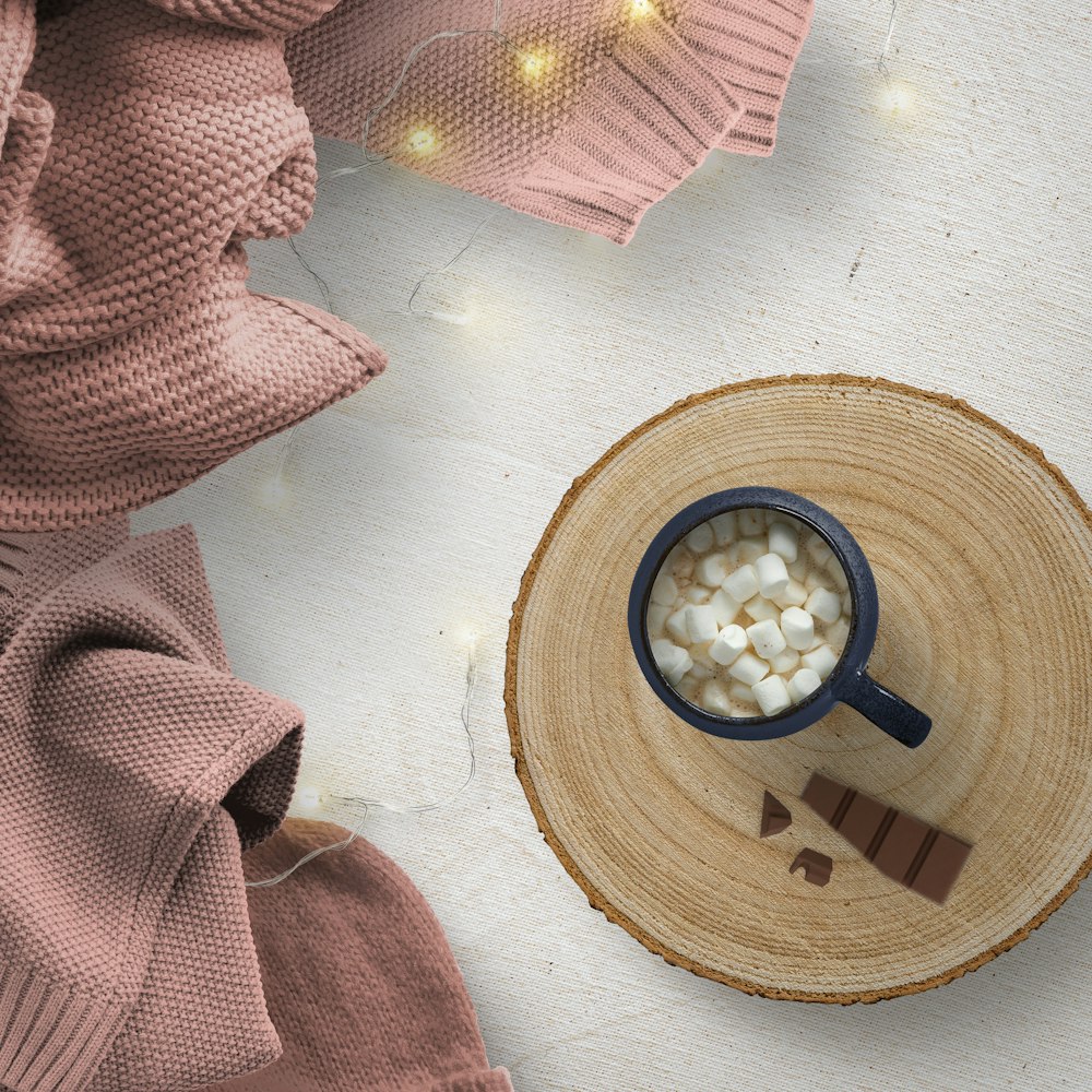 a cup filled with marshmallows on top of a wooden table