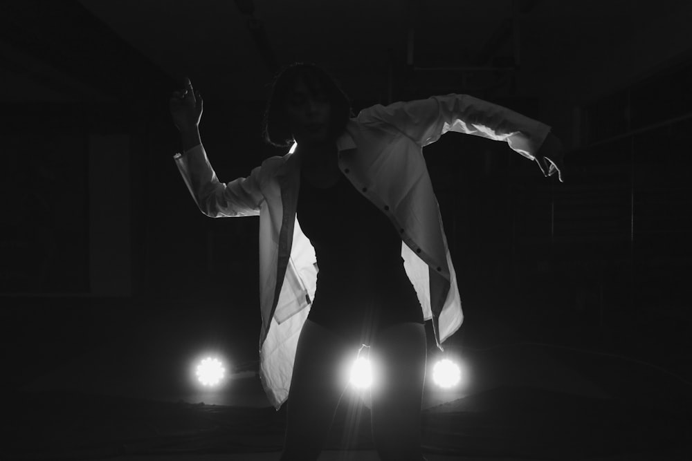Una mujer parada en la oscuridad con los brazos extendidos