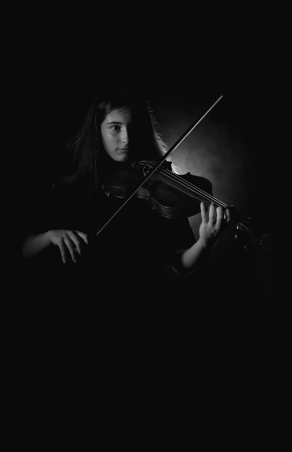 a woman playing a violin in the dark
