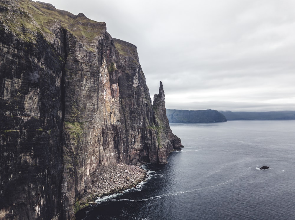 a boat is in the water near a rocky cliff