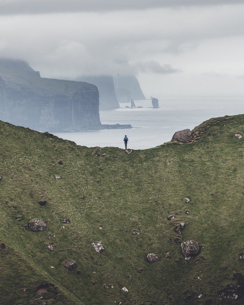 uma pessoa em pé no topo de uma colina coberta de grama