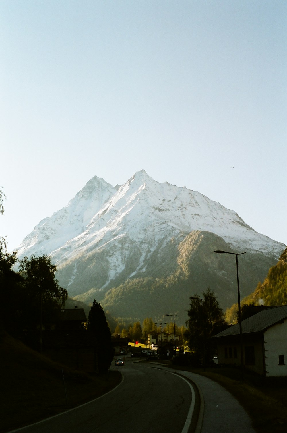 a snow covered mountain towering over a small town