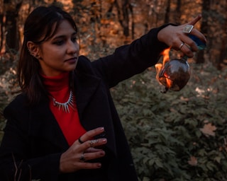 a woman holding a tea pot in a forest