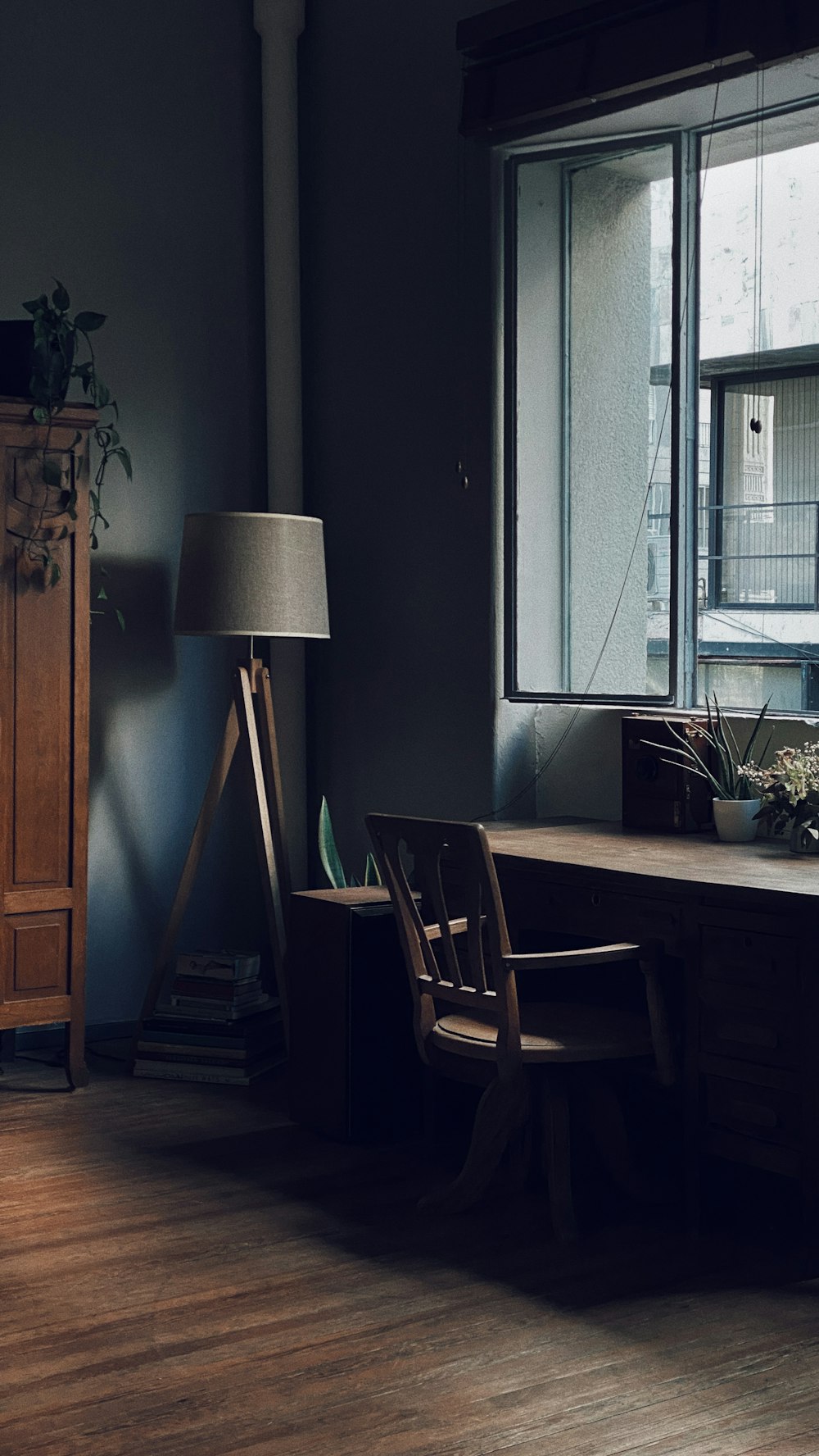 a room with a desk, chair, lamp and window