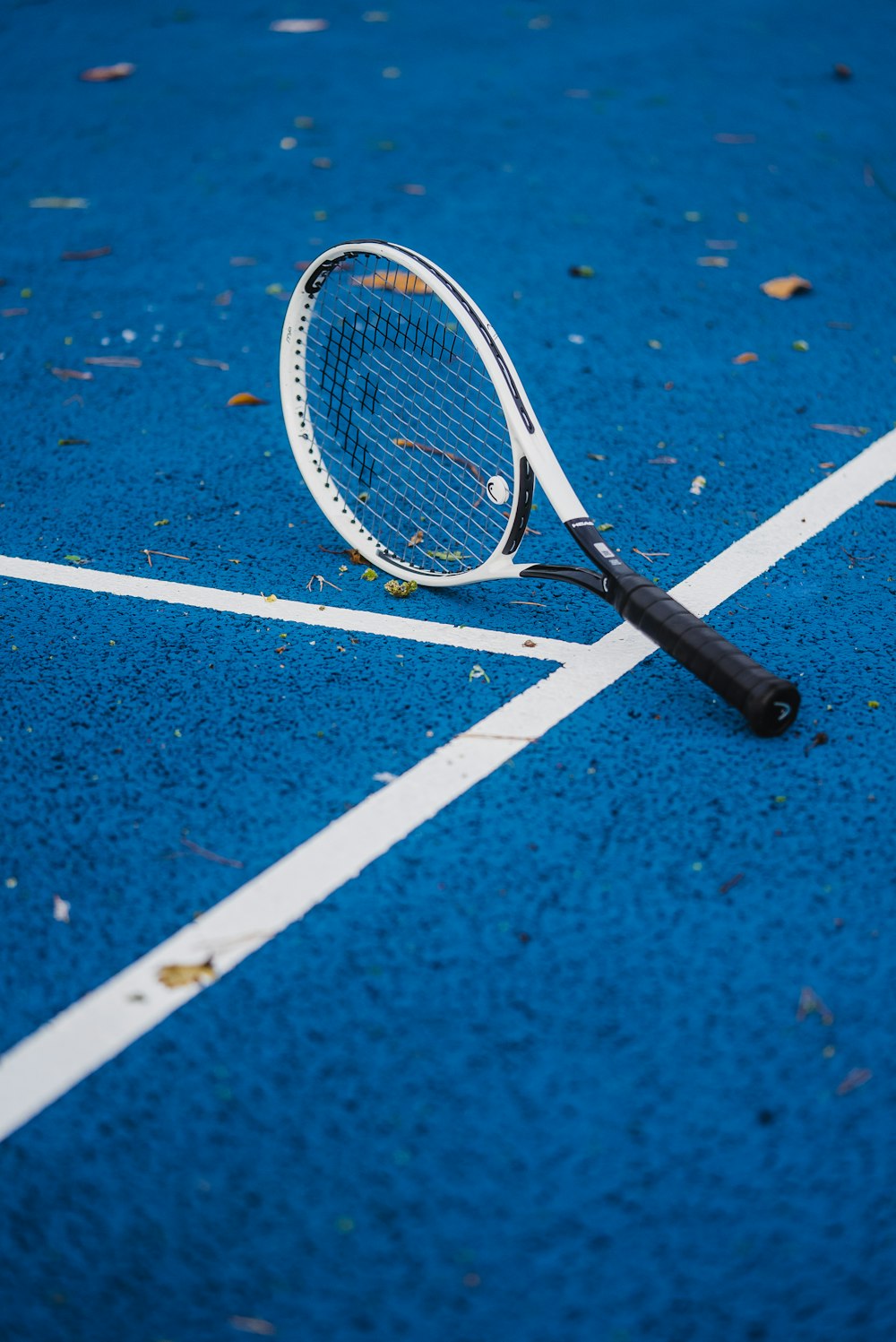 una raqueta de tenis acostada en una cancha de tenis azul