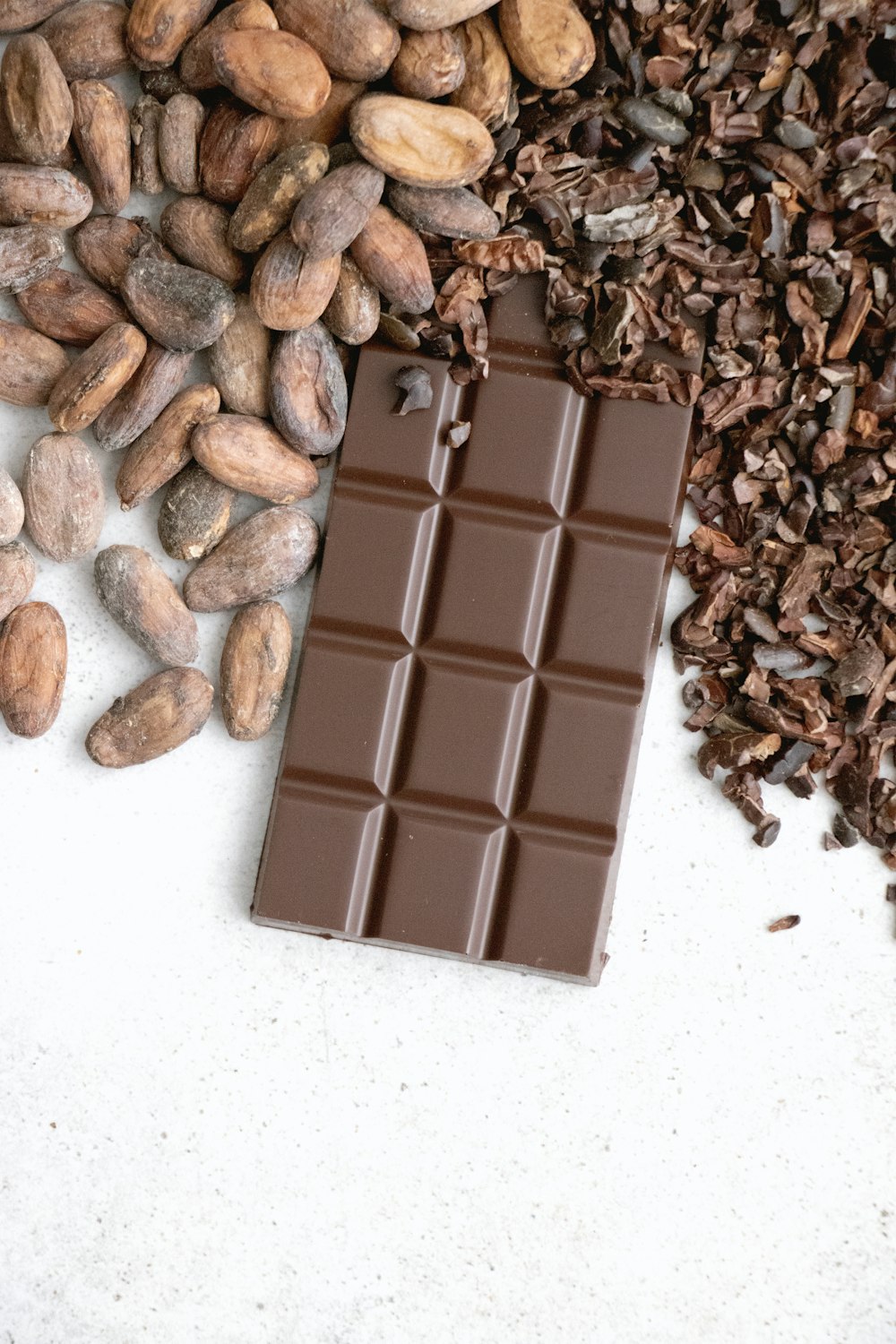 eine Tafel Schokolade neben einem Haufen Nüsse