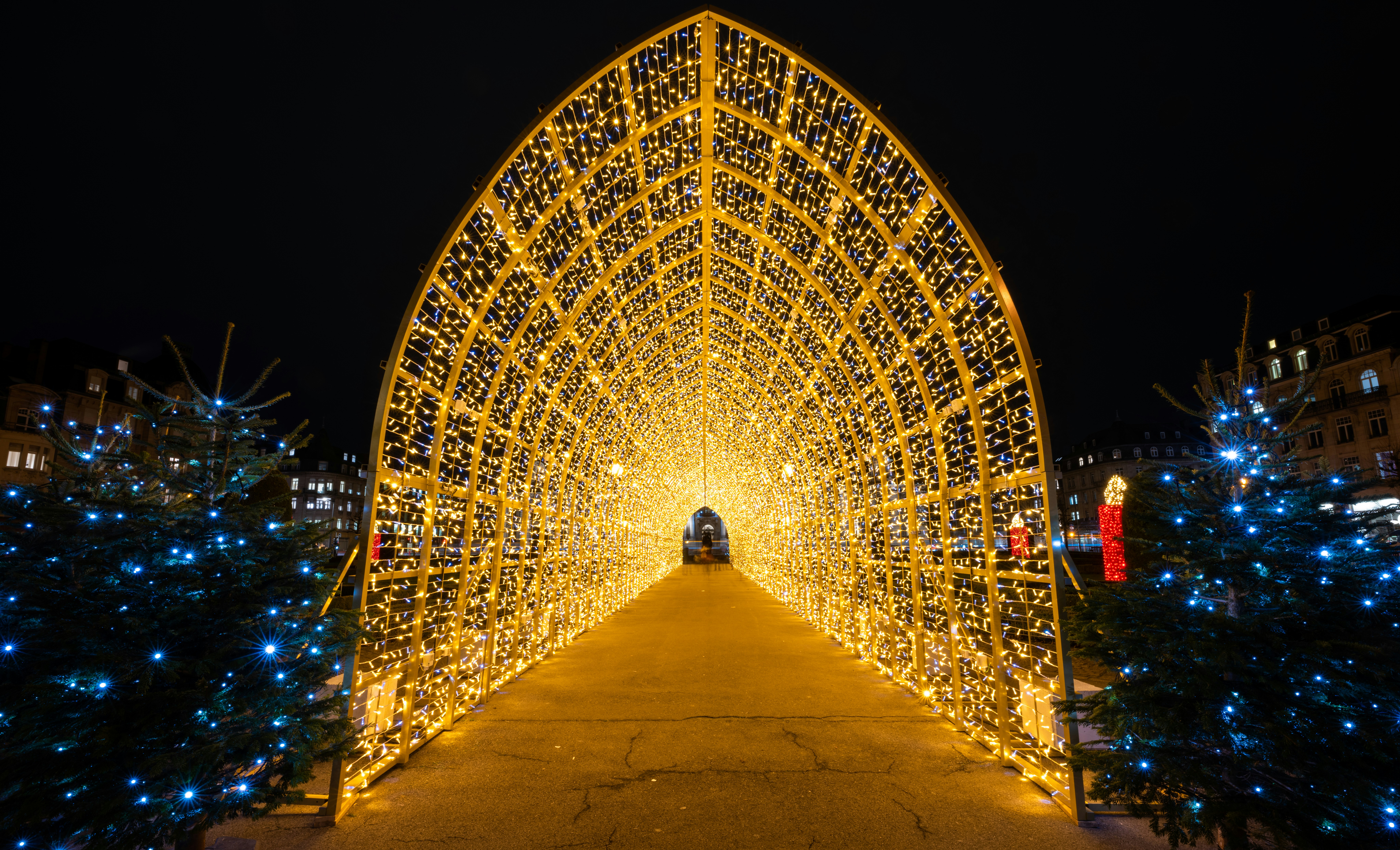 a large arch covered in christmas lights at night