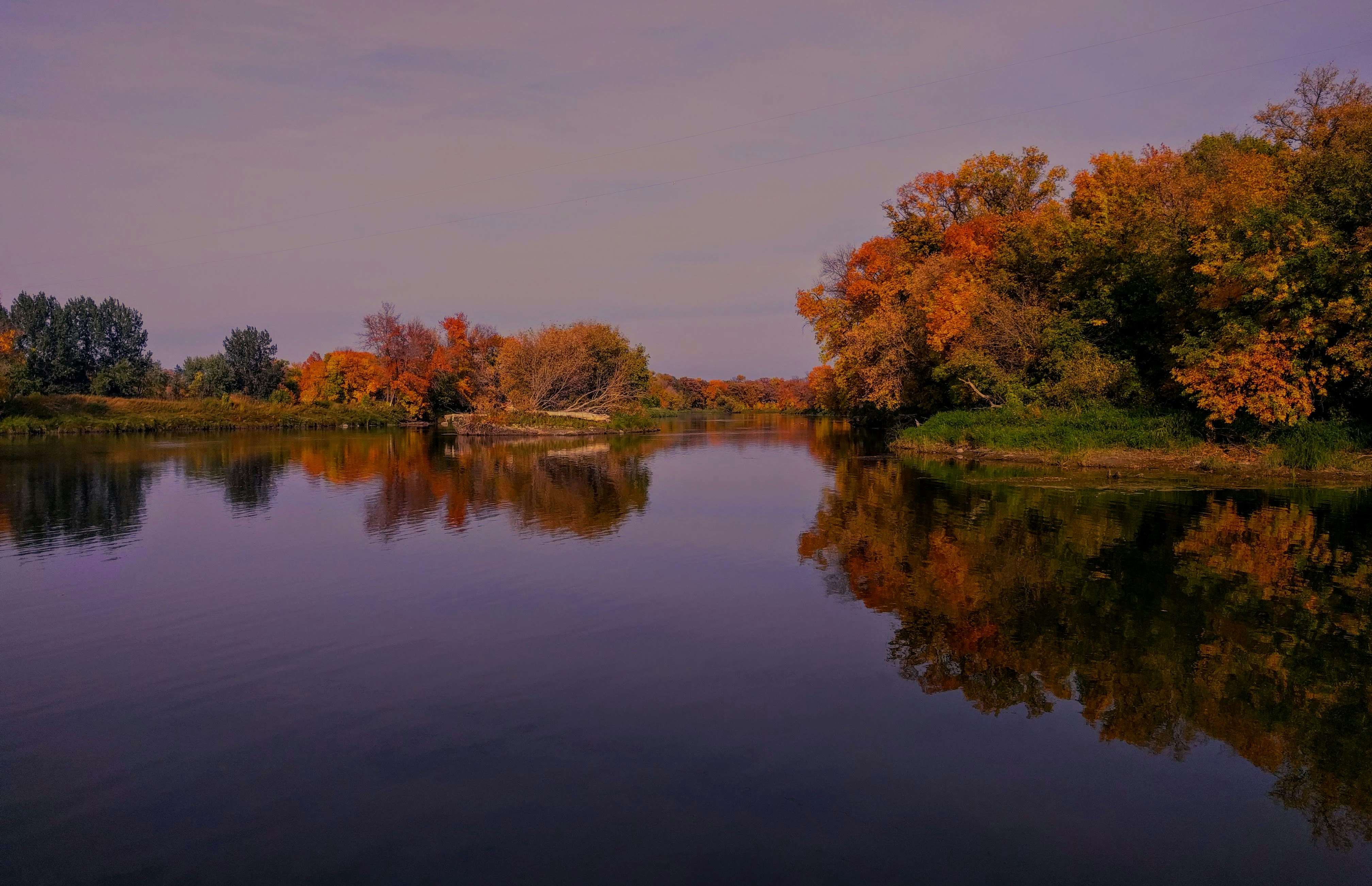 Fall colors on the Little Red River banks with orange and red foliage reflected in clear water
