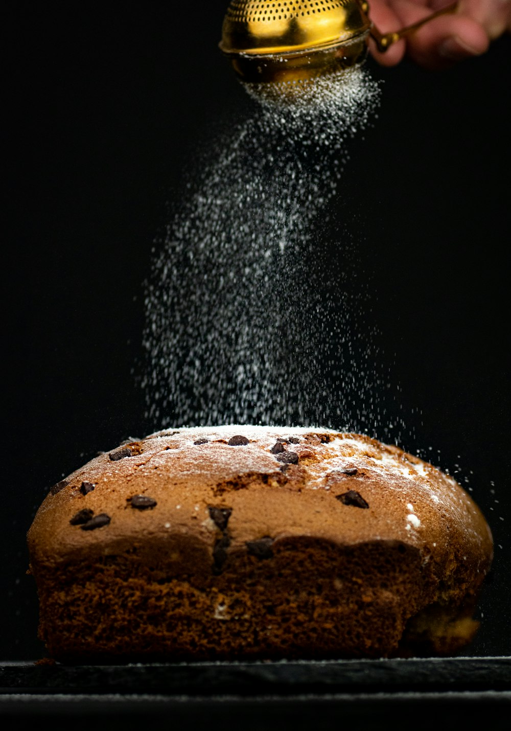 Eine Person streut Zucker auf einen Kuchen