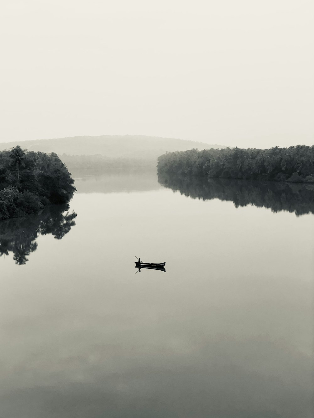 a boat floating on top of a lake next to a forest