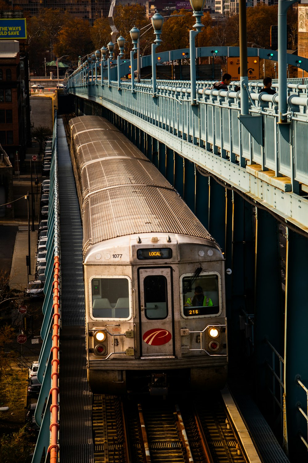 a silver train traveling down train tracks next to a tall building