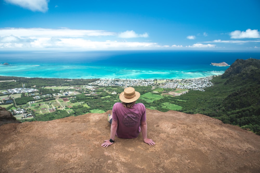 a man sitting on top of a mountain overlooking the ocean