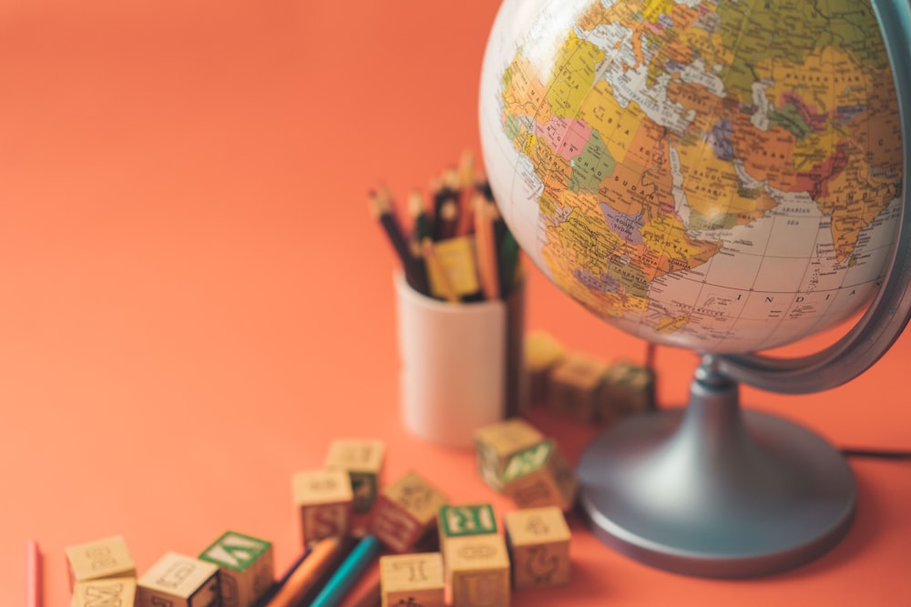 a globe, pencils, and a cup of pencils on a table