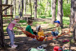 a group of kids sitting in a hammock in the woods