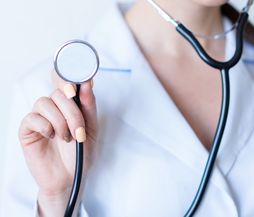 a woman in a white shirt holding a stethoscope