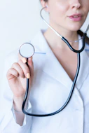 a woman in a white shirt holding a stethoscope