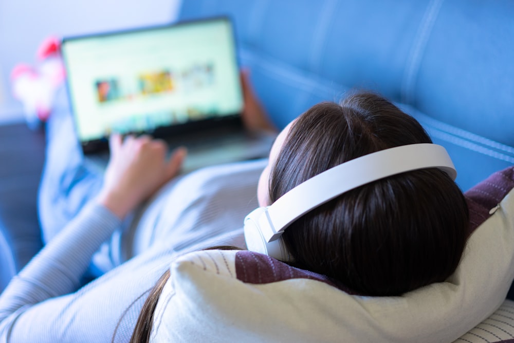 a person laying on a couch with a laptop