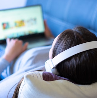 a person laying on a couch with a laptop