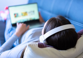 a person laying on a couch with a laptop