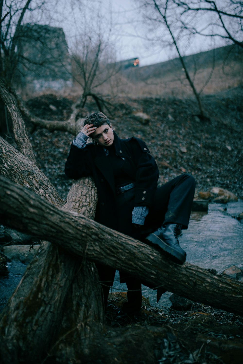 a man sitting on top of a tree branch next to a river