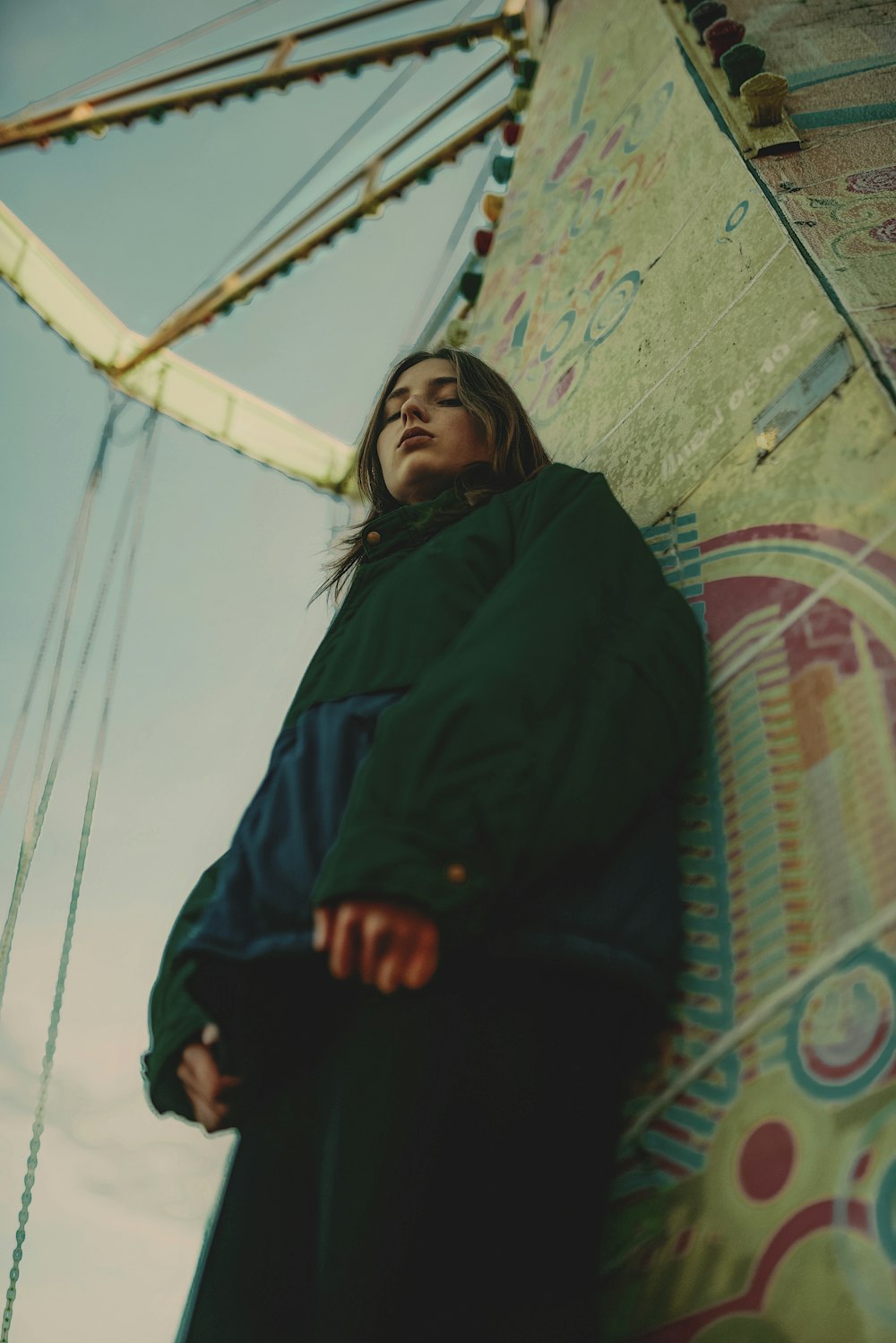 a woman leaning against a wall with a ferris wheel in the background