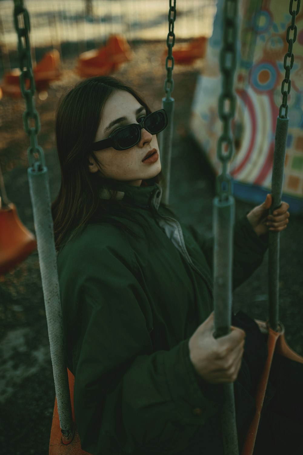 a woman wearing sunglasses sitting on a swing