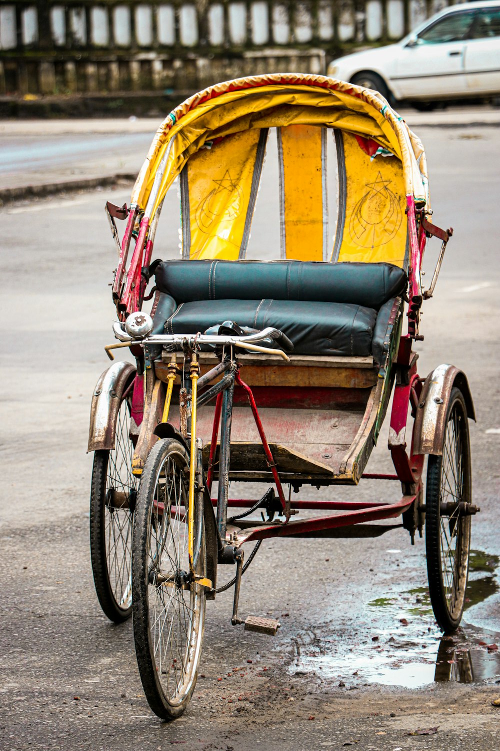 a yellow and red rickshaw sitting on the side of a road