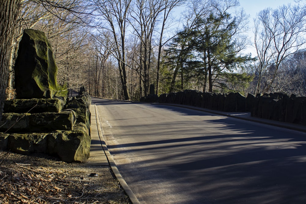 a street with a stone wall and trees