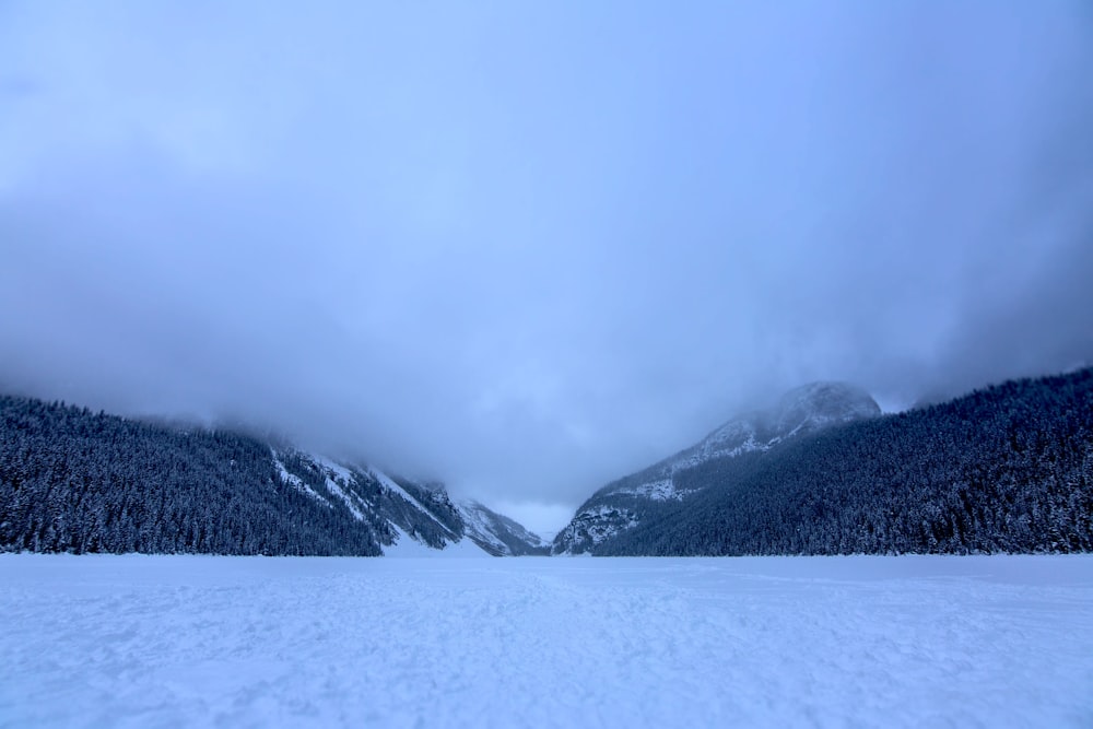 a snow covered field with mountains in the background