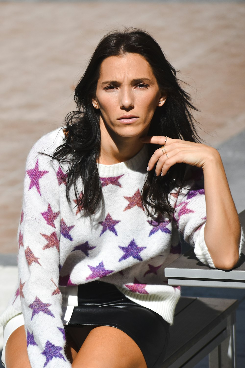 a woman sitting on a bench with her hand on her chin