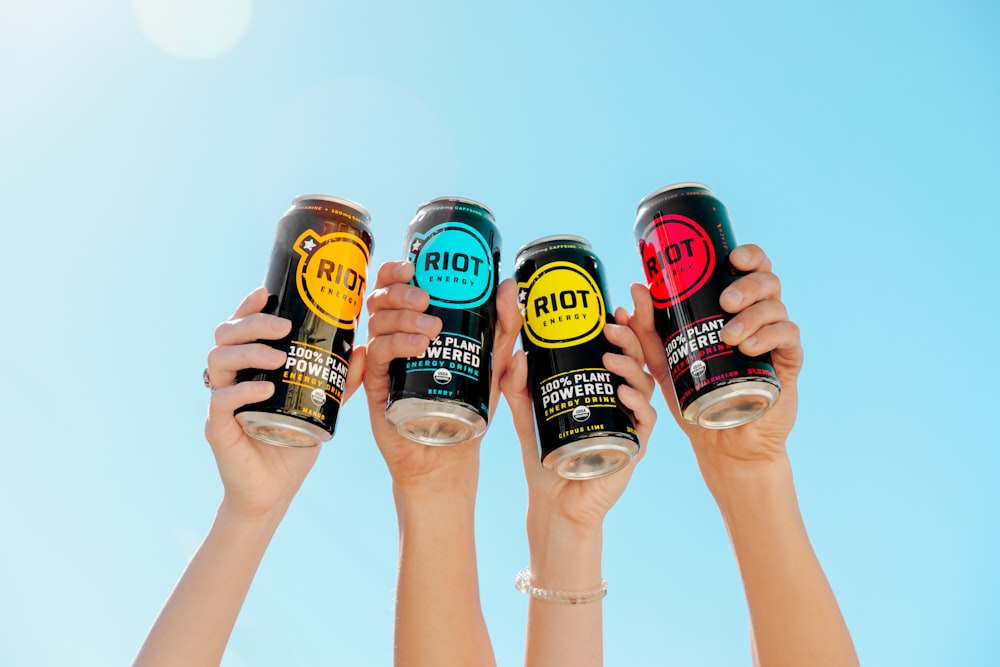 a group of people holding up cans of soda