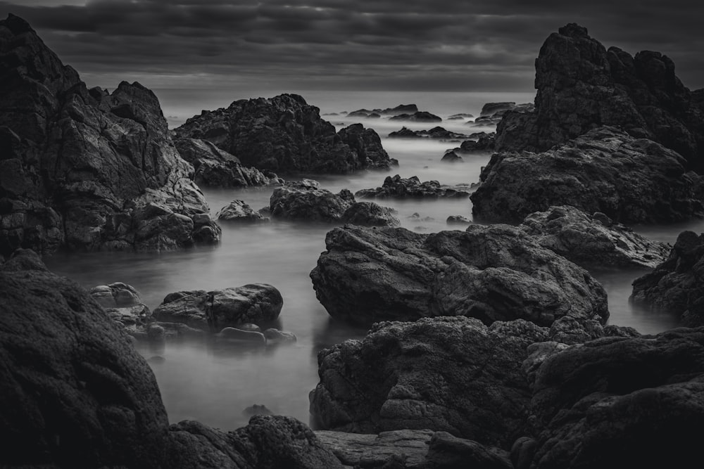 a black and white photo of rocks in the ocean