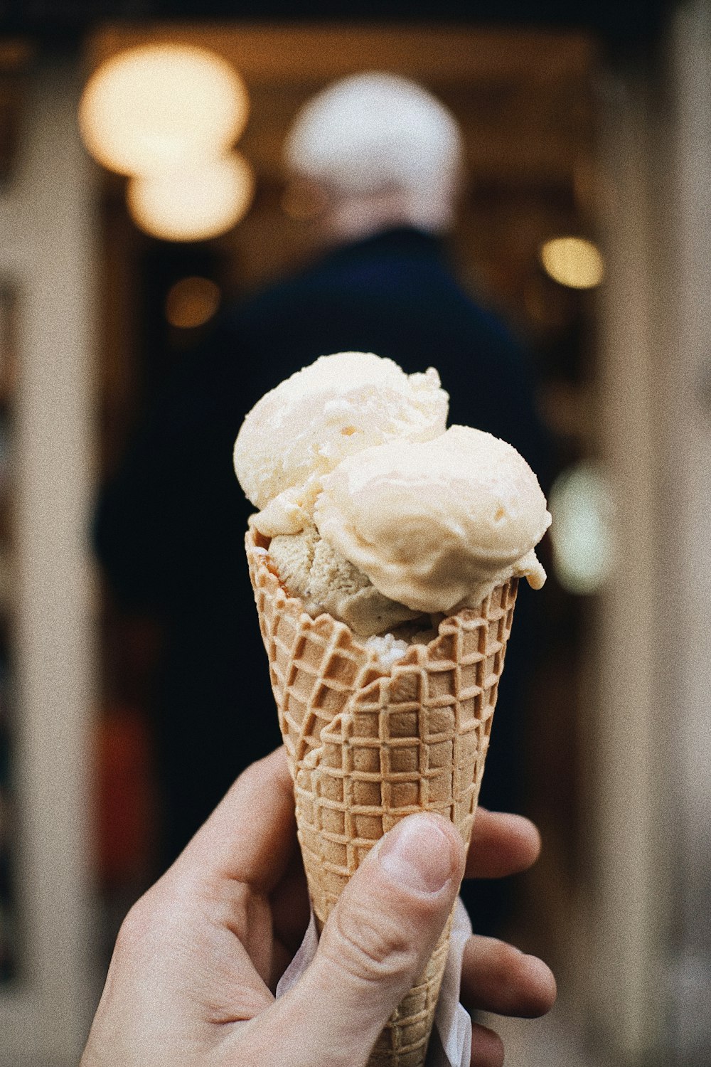 a hand holding a cone of ice cream