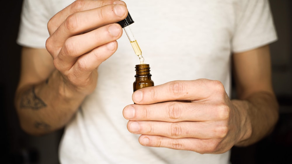 a man holding a small bottle with a dropper in it