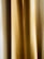 A close-up view of golden beige curtains with soft, vertical folds. The texture appears smooth, and the light creates subtle gradients.