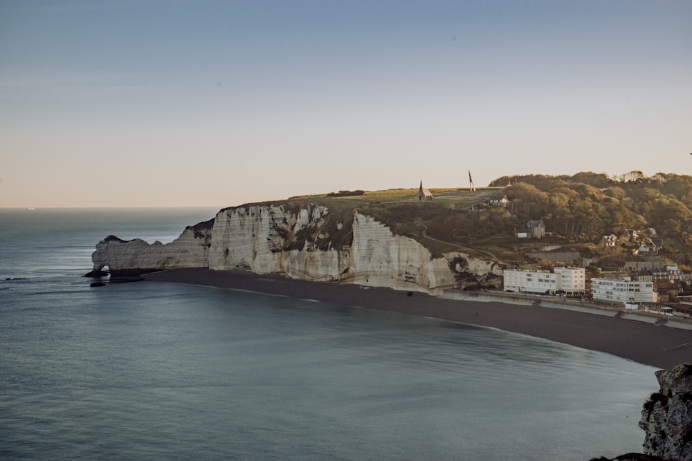 a beach next to a cliff with houses on it