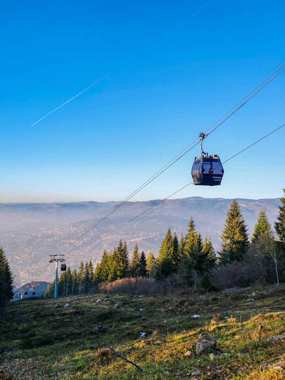 a ski lift going up a hill with a view of the city below