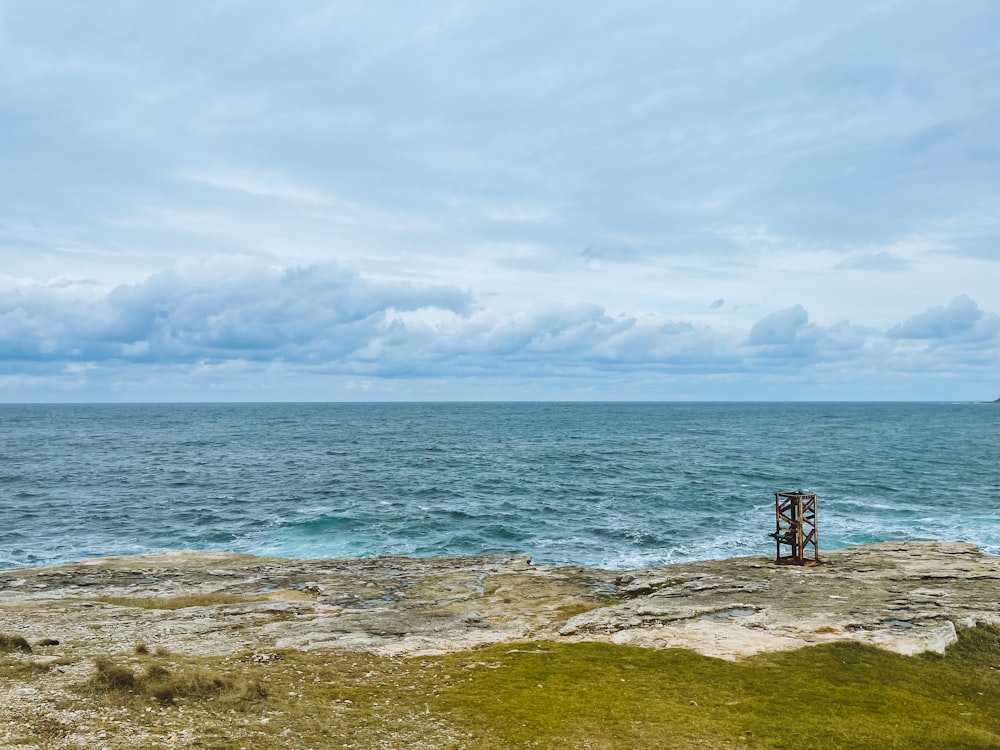 a bench sitting on the edge of a cliff overlooking the ocean