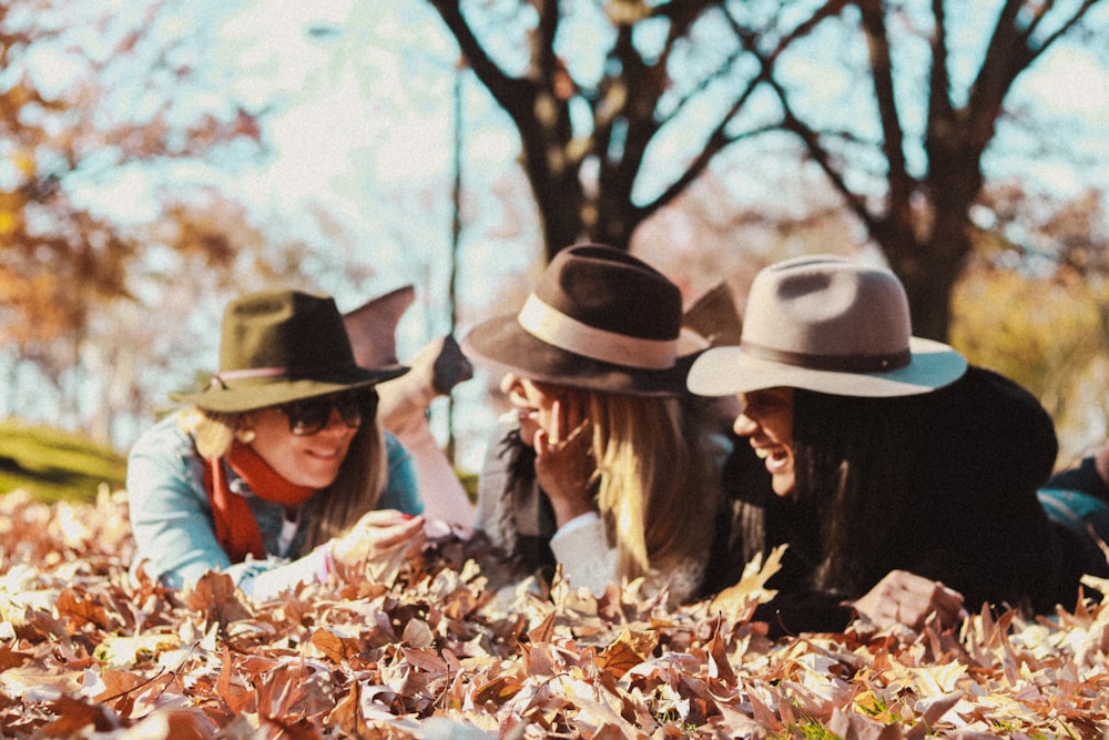 a group of women laying on top of a pile of leaves