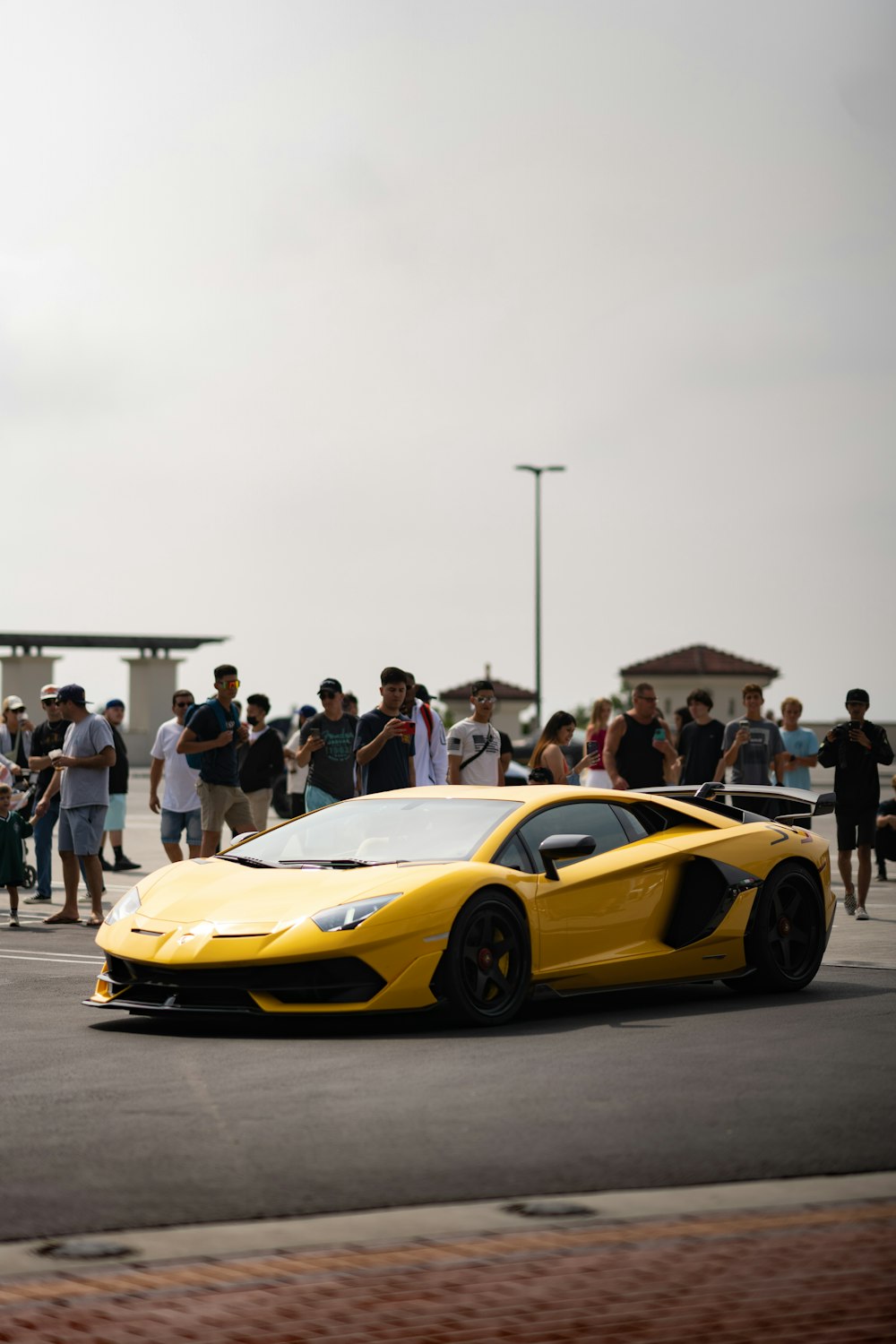 a yellow sports car parked in front of a crowd of people