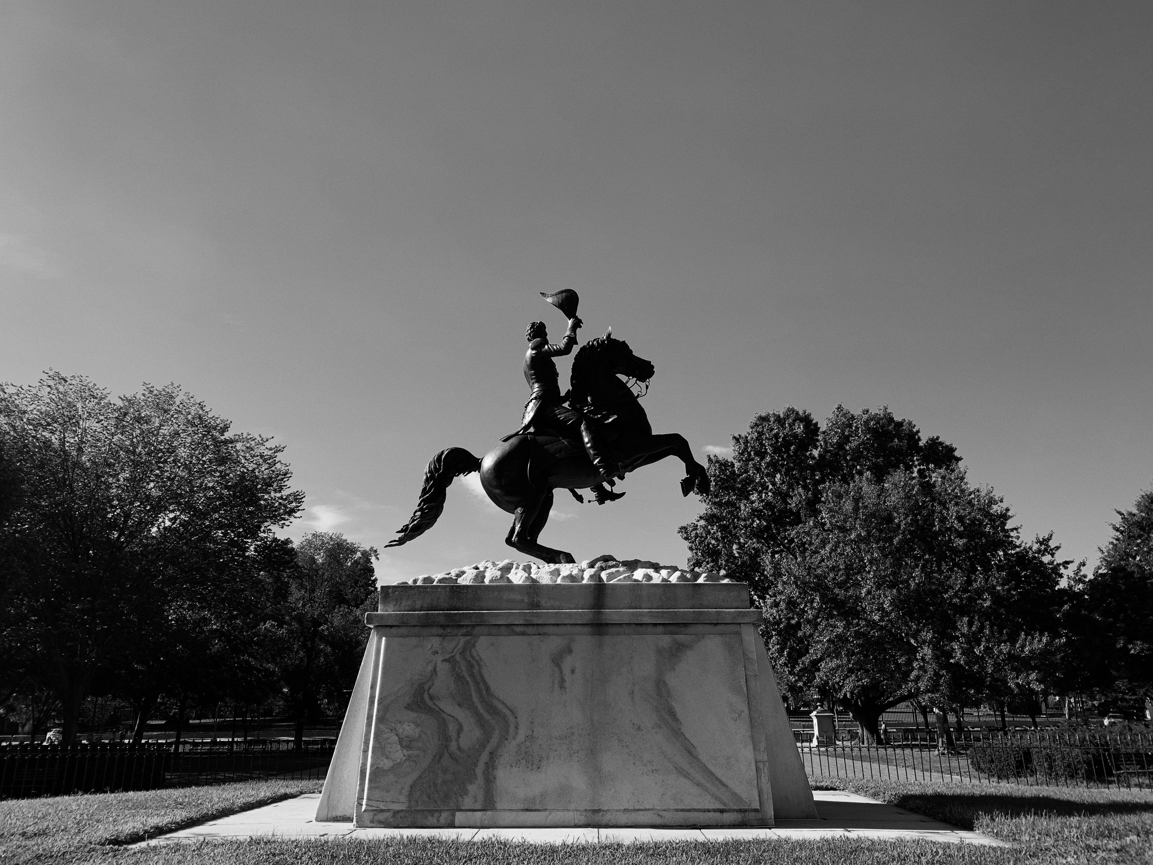 a black and white photo of a statue of a man riding a horse