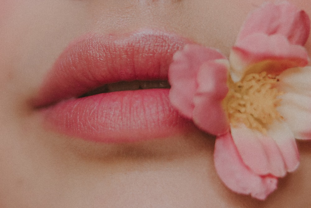 a close up of a woman's lips with a flower in her mouth
