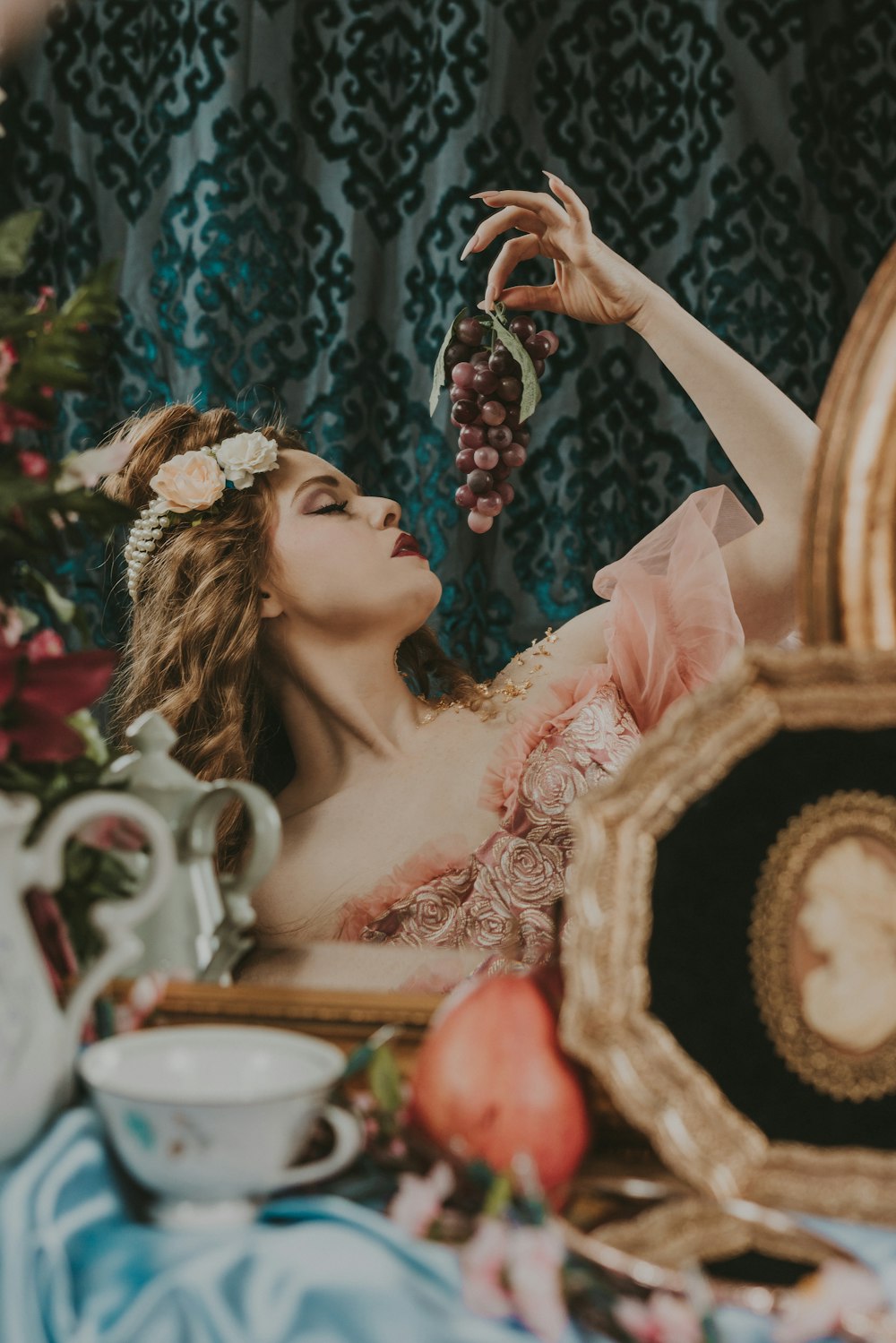 a woman in a pink dress holding a bunch of grapes