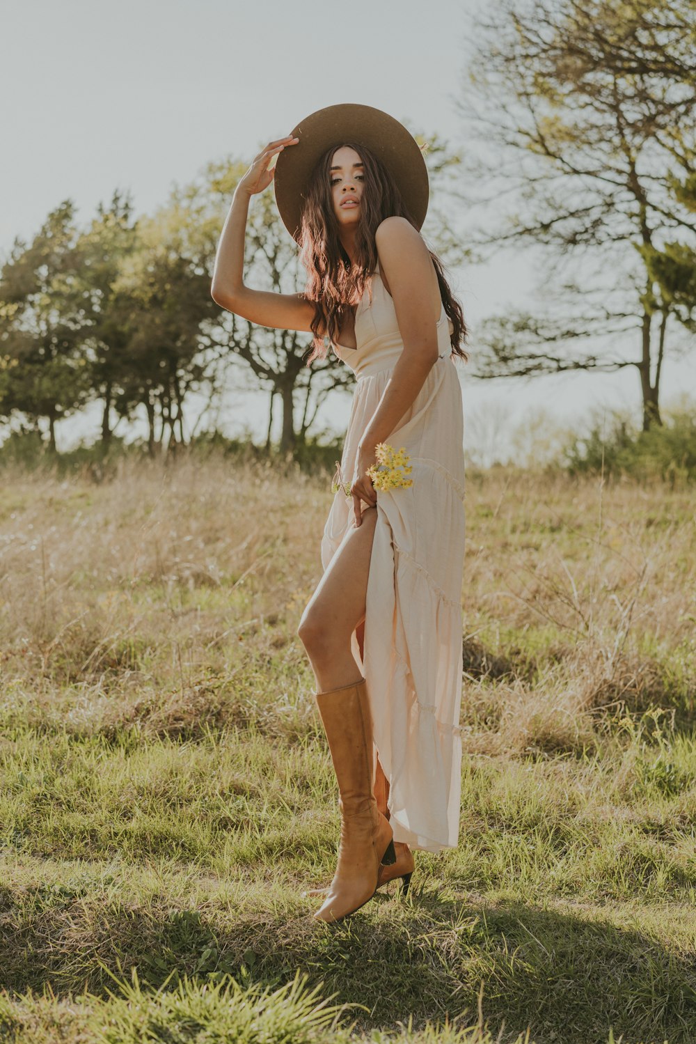 a woman standing in a field wearing a hat