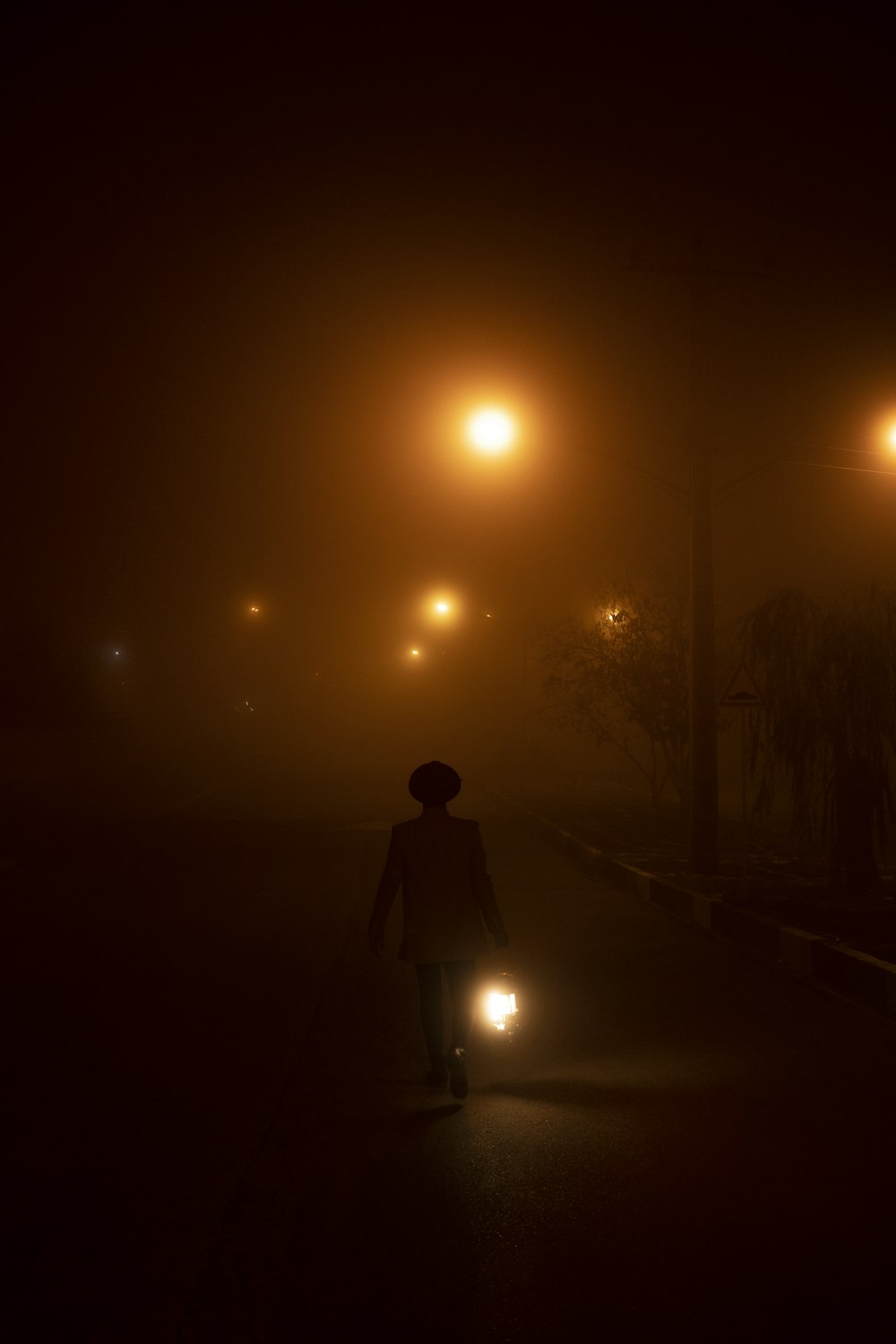 uma pessoa andando por uma rua à noite com uma luz acesa