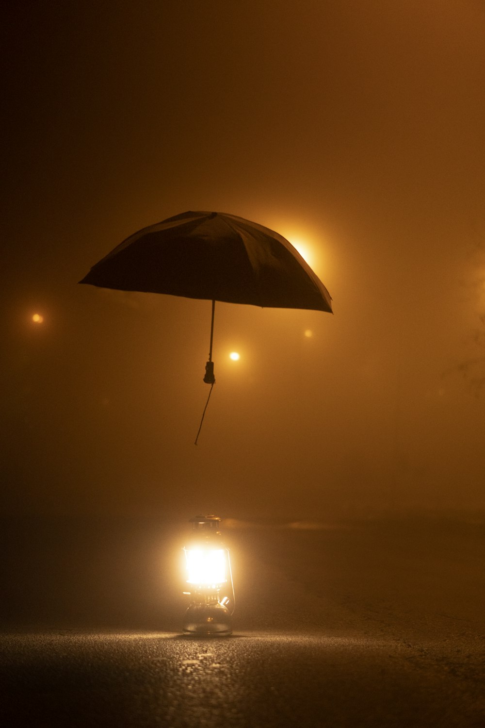 a person holding an umbrella over a car in the fog