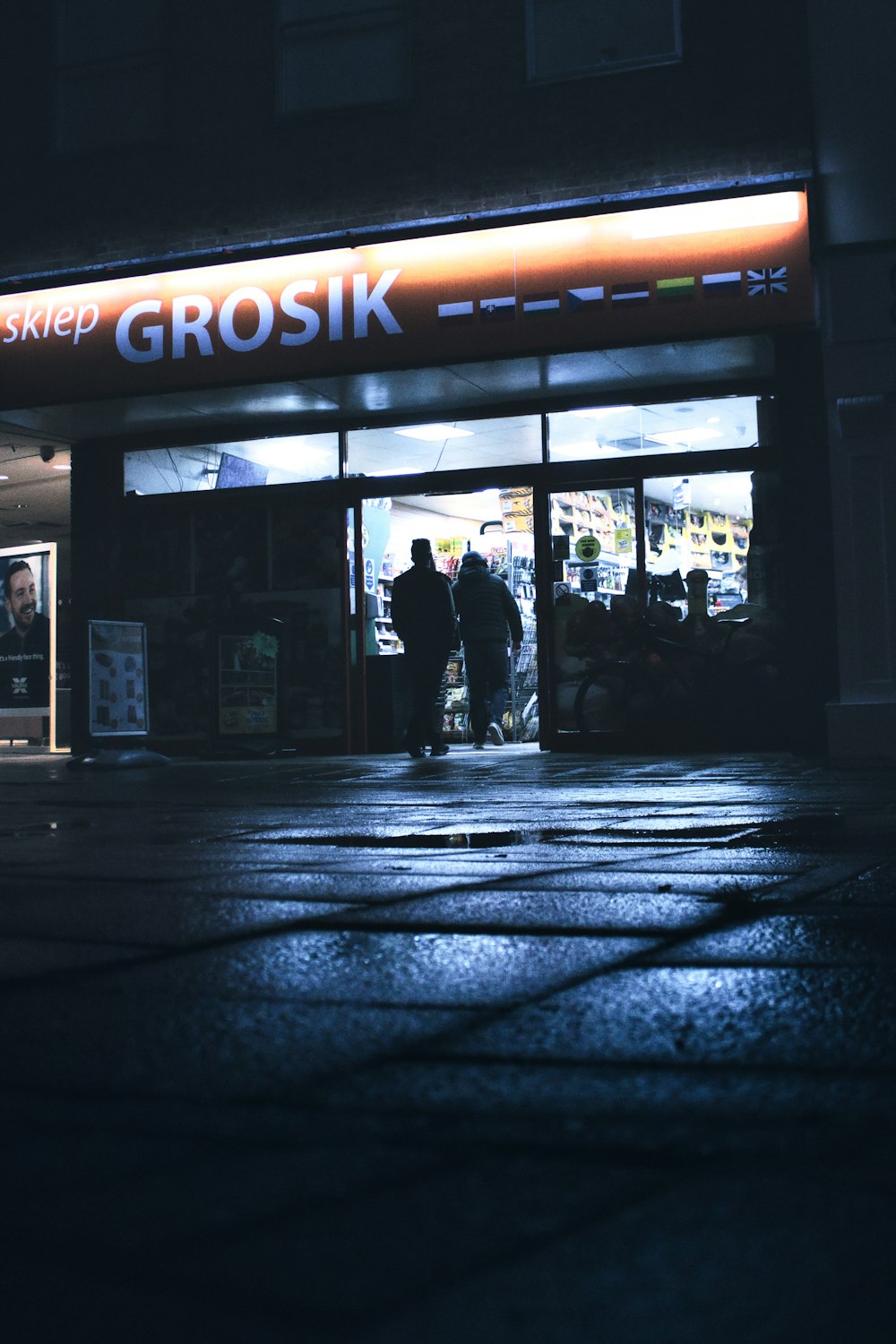 a group of people standing outside of a store at night