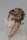 A person with soft features gently rests their face on their hand. Light-colored butterflies are delicately positioned on their face and ear, adding an ethereal touch. The overall appearance is dreamlike, with a soft focus and muted tones.