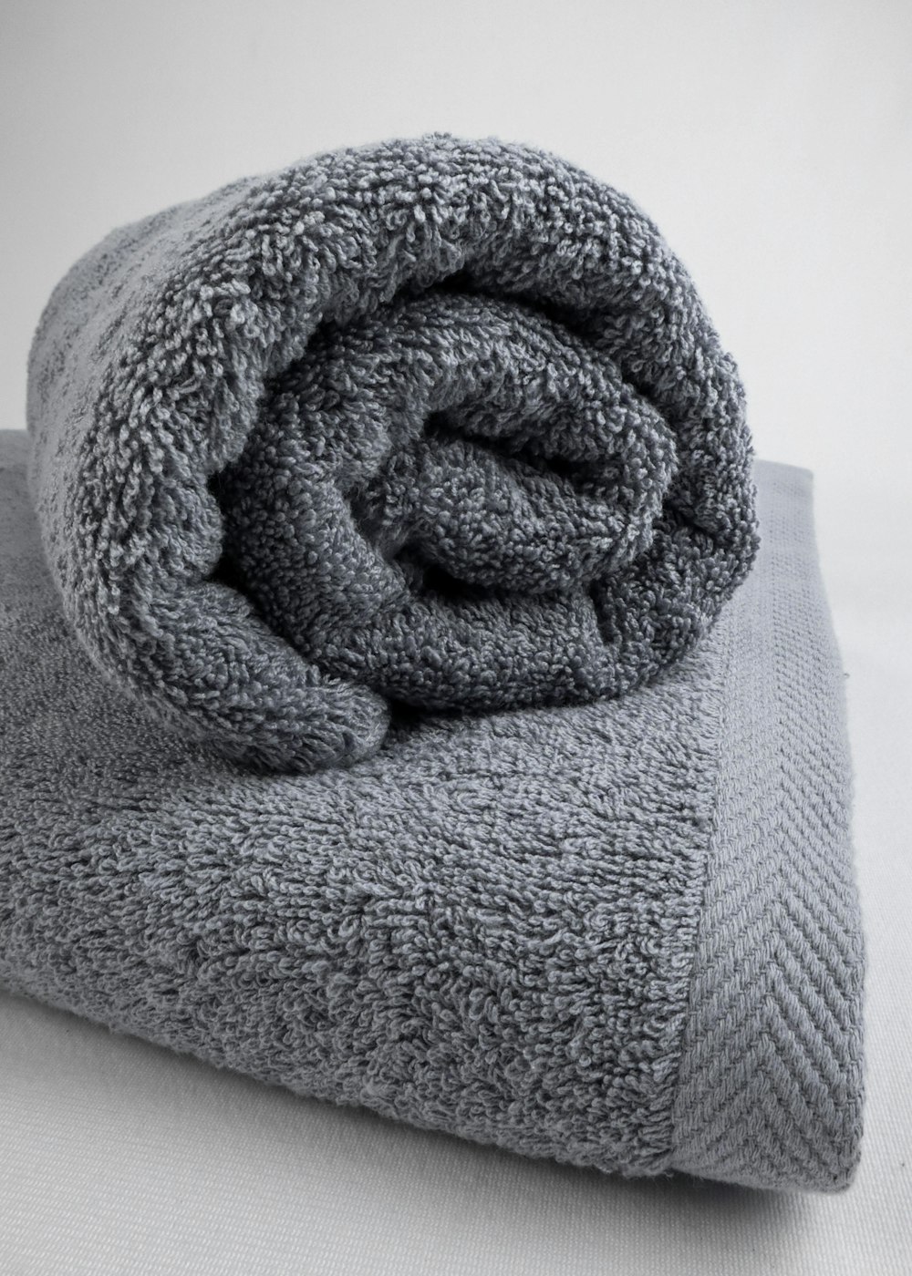 uma toalha cinza dobrada em cima de uma cama